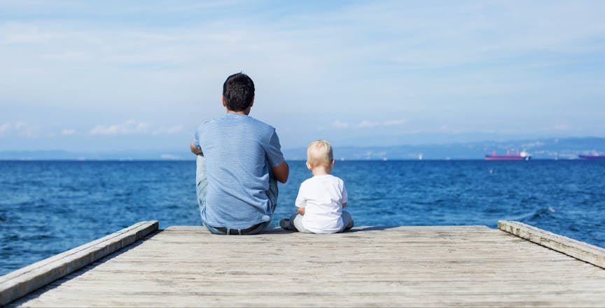 Father with son sitting on the sea pier
